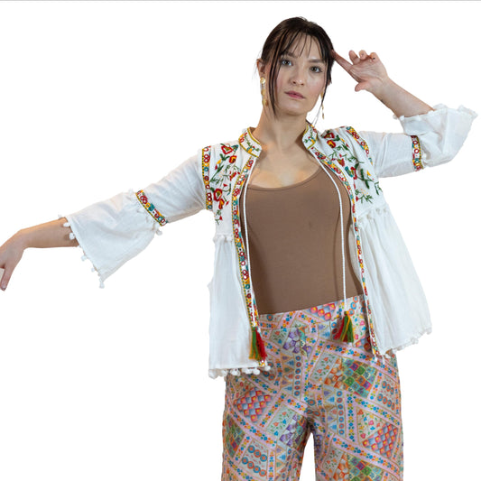 Woman wearing a colorful outfit with a white jacket and patterned pants on a white background